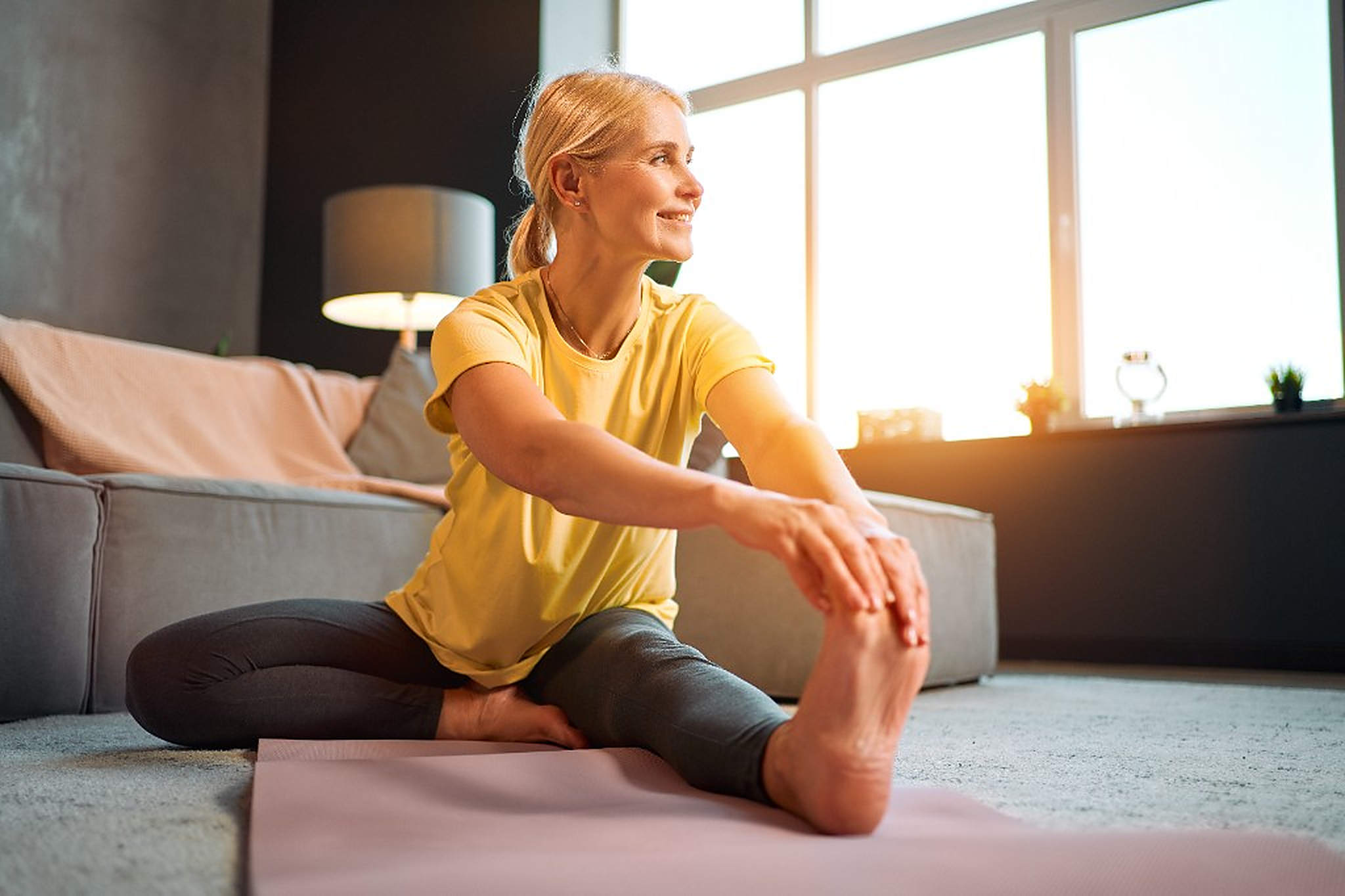 Woman stretching at home in warm morning light